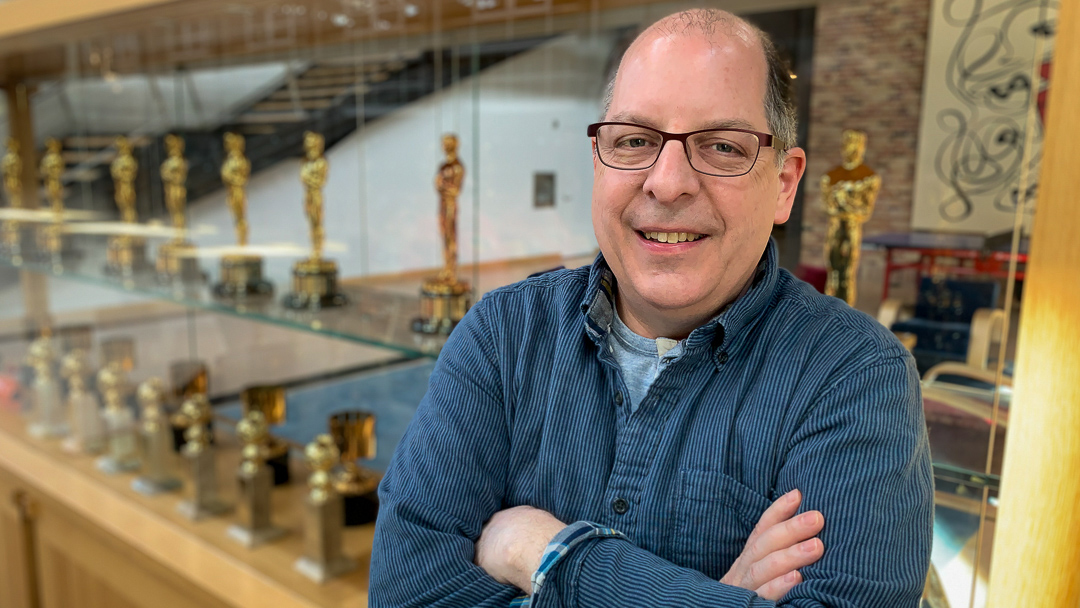 Rice University Computer Science alumnus Eric Salituro poses in front of Pixar's trophy case.