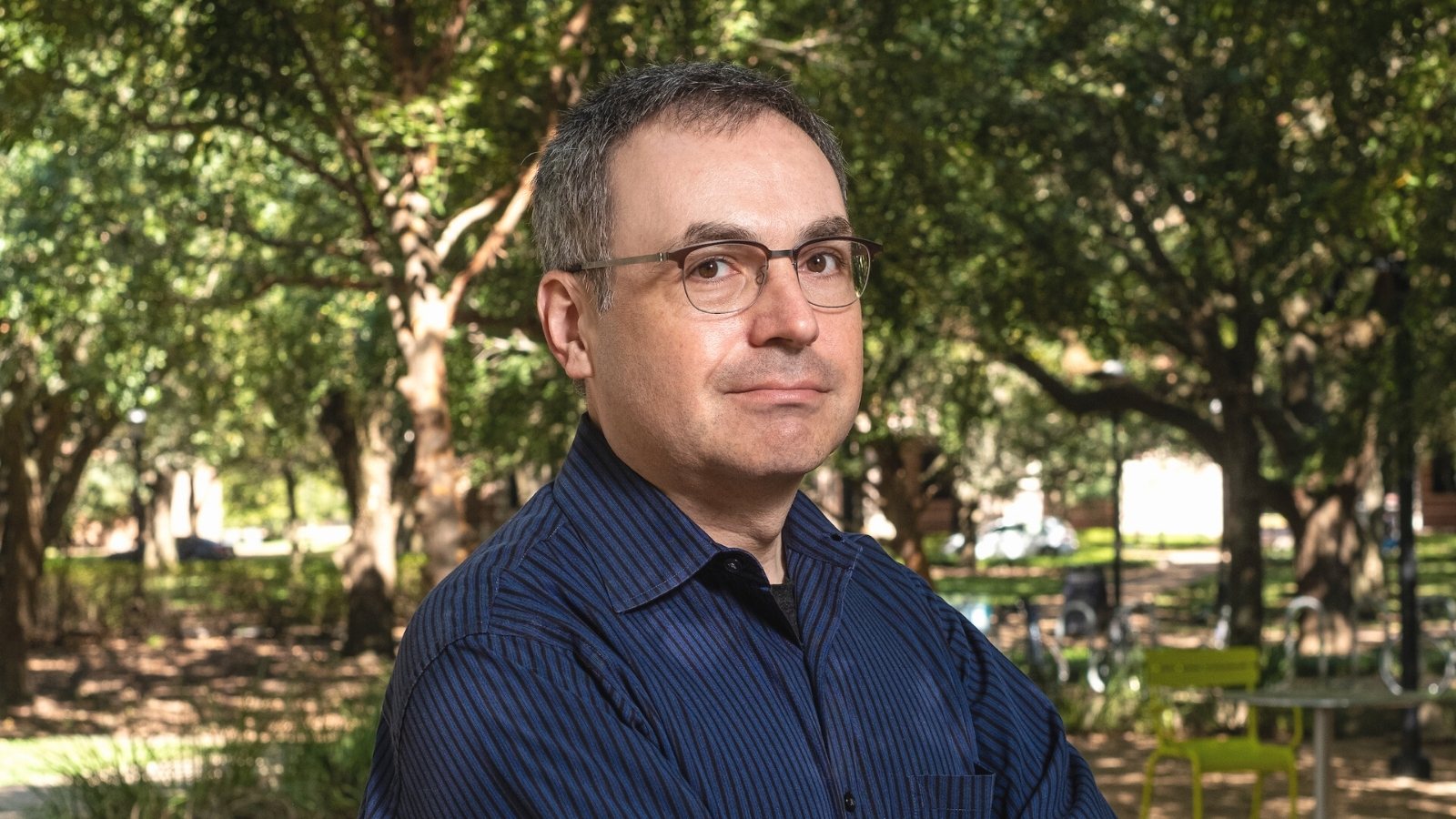 Dan Wallach standing outside by trees on Rice University campus