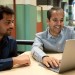 Aditya Desai and Anshumali Shrivastava sit in front of a laptop and talk inside Duncan Hall at Rice University